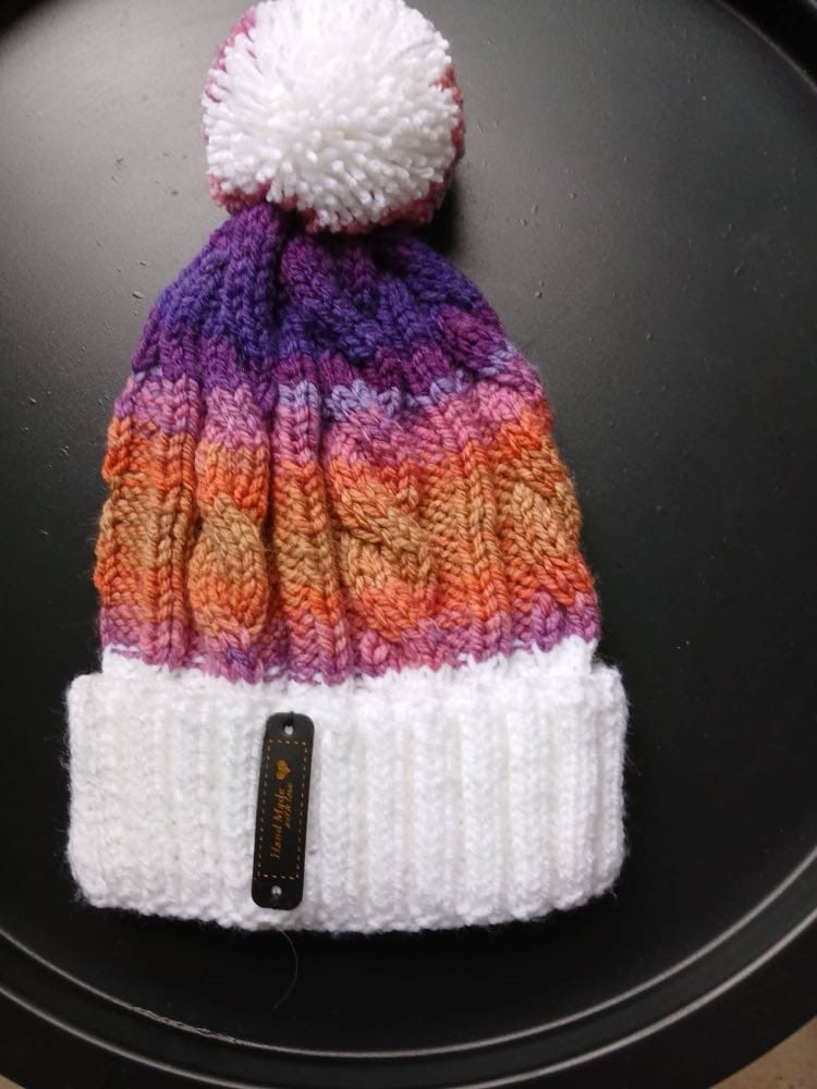Cable-knit bobble hat striped violet, pink, orange and caramel, with a white cuff and white bobble